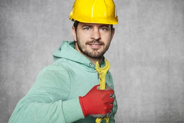 Smiling Worker Holding A Yellow Wrench